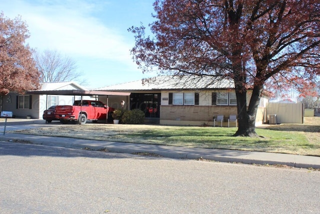 ranch-style house with a carport, a front yard, brick siding, and central air condition unit