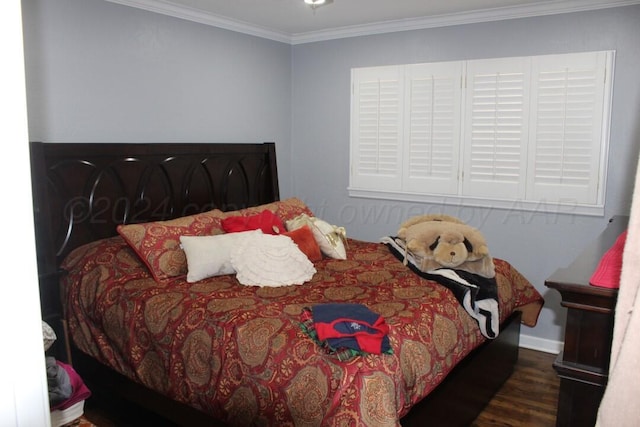 bedroom with ornamental molding, baseboards, and wood finished floors