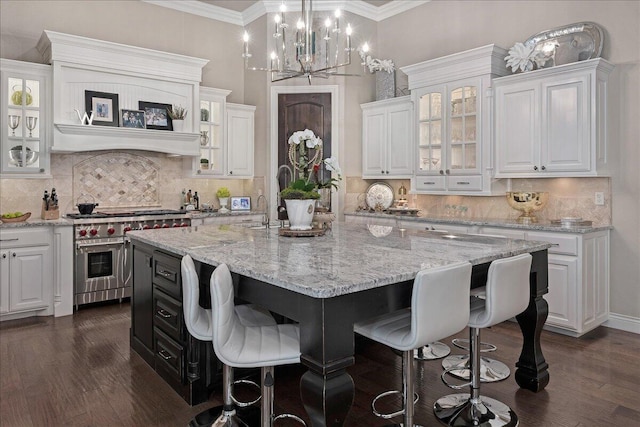 5708 Barrington Ct, Amarillo, TX 79119 - kitchen with white cabinets, double oven range, a center island with sink, a breakfast bar area, and dark wood-style floors