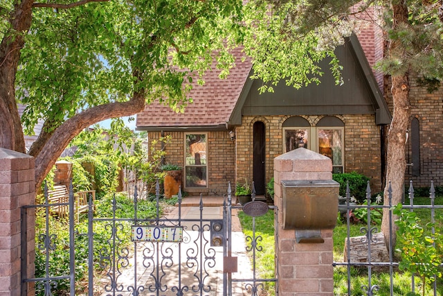 907 Broadmoor St, Amarillo, TX 79106 - tudor house featuring roof with shingles, brick siding, a fenced front yard, and a gate