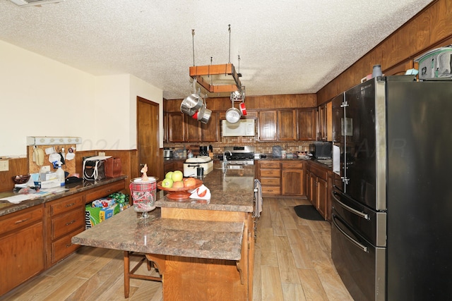 kitchen featuring appliances with stainless steel finishes, a center island, light hardwood / wood-style floors, and a textured ceiling