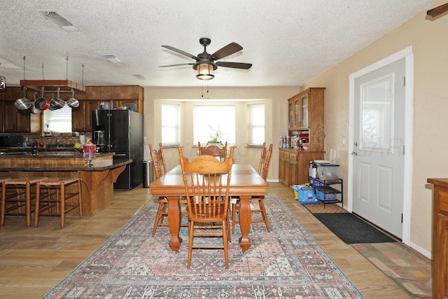 dining area with light hardwood / wood-style floors and a textured ceiling