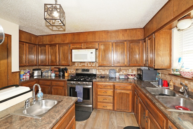 kitchen featuring gas range, sink, a textured ceiling, and light wood-type flooring