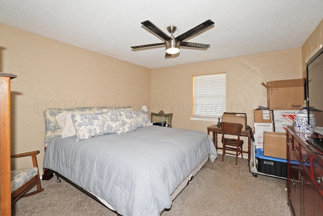 bedroom with ceiling fan, light colored carpet, and a textured ceiling