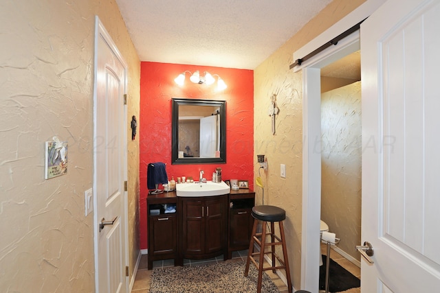 bathroom featuring vanity, a textured ceiling, tile patterned floors, and toilet