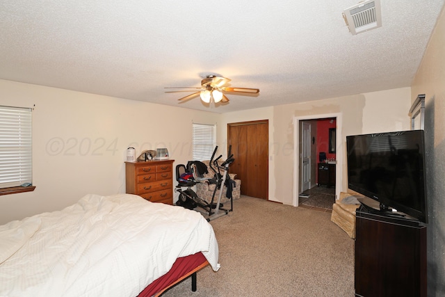 carpeted bedroom with ceiling fan and a textured ceiling