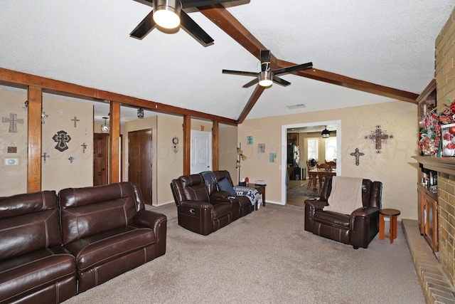 carpeted living room featuring lofted ceiling with beams, ceiling fan, a textured ceiling, and a brick fireplace