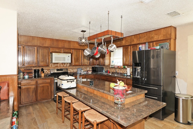 kitchen with a center island, sink, stainless steel appliances, backsplash, and a breakfast bar area