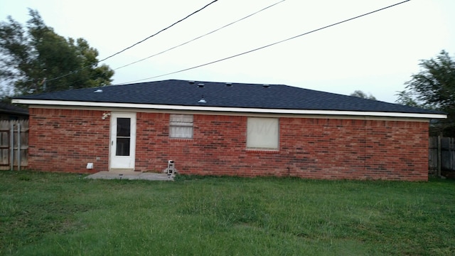 back of property with fence, brick siding, and a yard