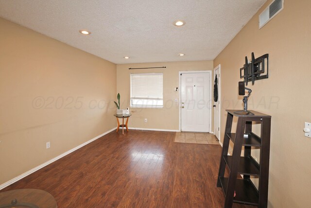 foyer with a textured ceiling, visible vents, baseboards, wood finished floors, and recessed lighting