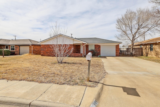 single story home featuring brick siding, concrete driveway, a garage, and fence