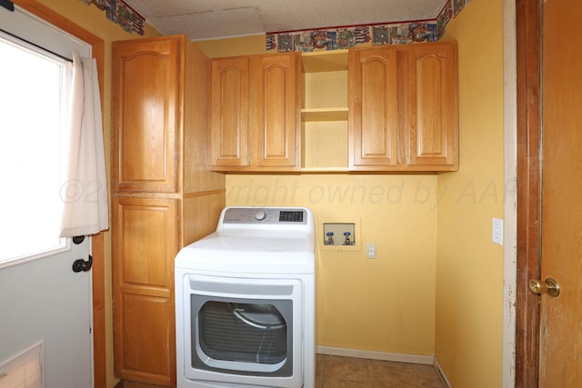 washroom featuring baseboards, cabinet space, washer / clothes dryer, and a textured ceiling