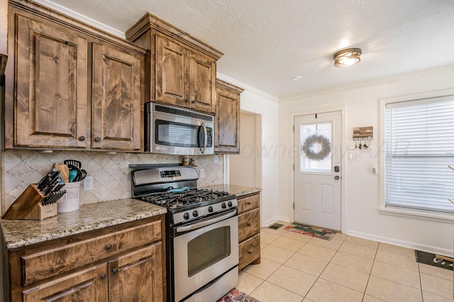 2000 3rd Ave, Canyon, TX 79015 - kitchen with appliances with stainless steel finishes, decorative backsplash, baseboards, light stone countertops, and crown molding