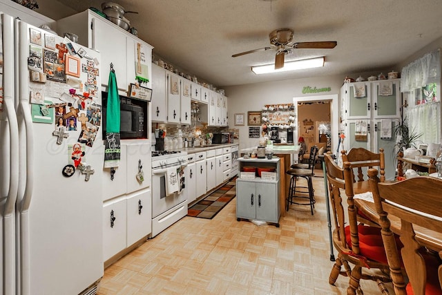 1010 E 3rd St, Clarendon, TX 79226 - kitchen featuring white appliances, ceiling fan, a kitchen bar, a kitchen island, and white cabinetry