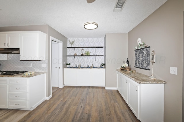 7426 Jameson Dr, Amarillo, TX 79121 - kitchen featuring under cabinet range hood, wood finished floors, white cabinets, stainless steel gas cooktop, and light stone countertops