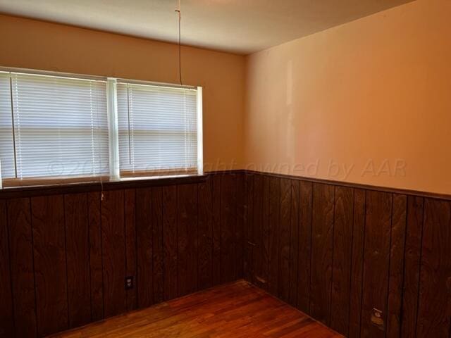 unfurnished room featuring dark hardwood / wood-style flooring and wood walls