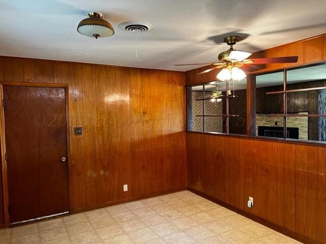 spare room featuring wood walls and ceiling fan