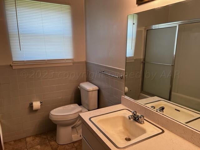 bathroom featuring tile walls, tile patterned floors, walk in shower, vanity, and toilet