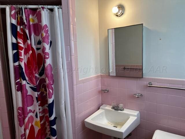 bathroom featuring tile walls, sink, and a shower with curtain