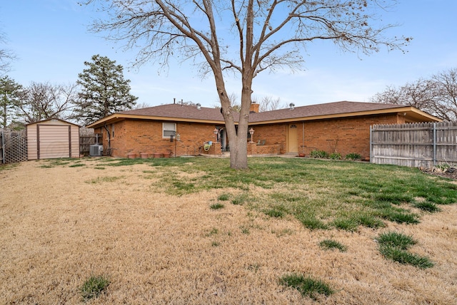 back of house featuring an outdoor structure, fence, a shed, brick siding, and a lawn