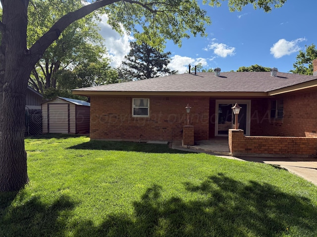 409 Thompson Ln, Canyon, TX 79015 - rear view of property featuring brick siding, a storage unit, a lawn, and an outbuilding