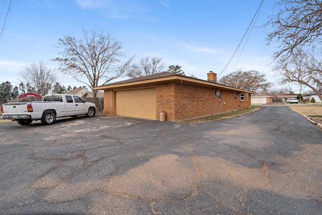 409 Thompson Ln, Canyon, TX 79015 - view of home's exterior featuring a chimney, brick siding, and a garage