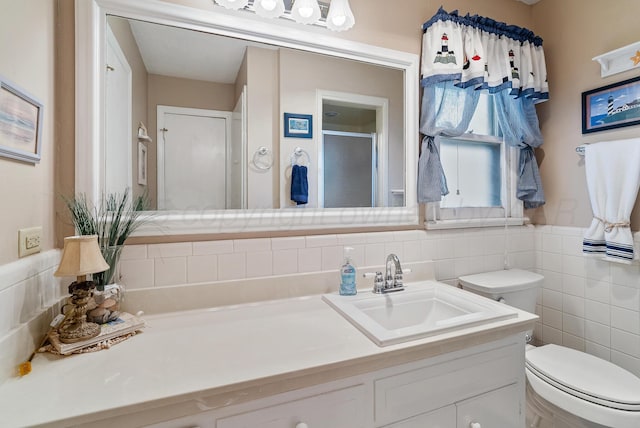 bathroom featuring toilet, tile walls, a shower stall, and vanity