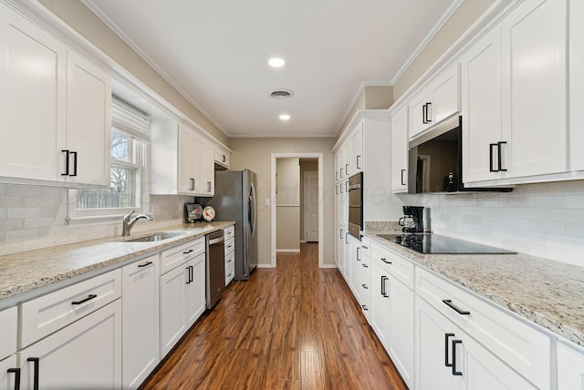 kitchen with crown molding, a sink, stainless steel appliances, baseboards, and white cabinetry