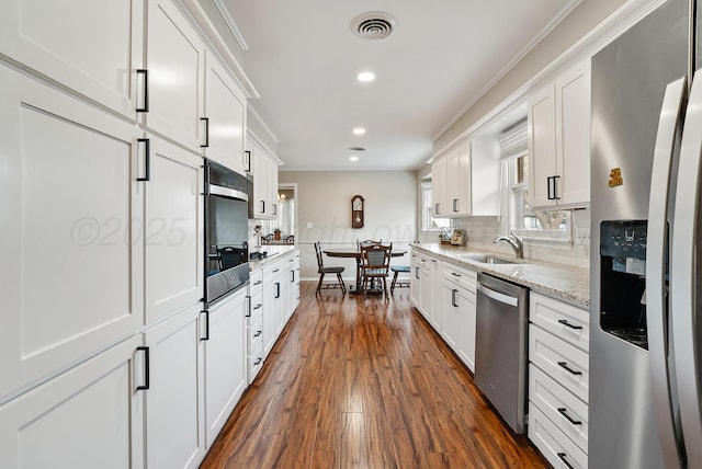 kitchen with appliances with stainless steel finishes, ornamental molding, white cabinetry, visible vents, and dark wood-style floors