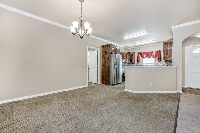 7110 Bennett St, Amarillo, TX 79119 - kitchen featuring stainless steel fridge with ice dispenser, light carpet, a chandelier, ornamental molding, and arched walkways