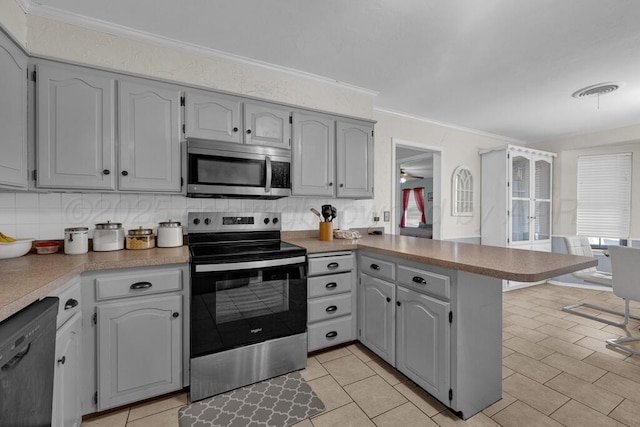 kitchen featuring stainless steel appliances, a peninsula, ornamental molding, and decorative backsplash