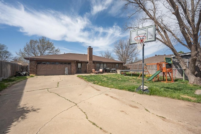 view of front of property with a front yard, an attached garage, a trampoline, a playground, and concrete driveway