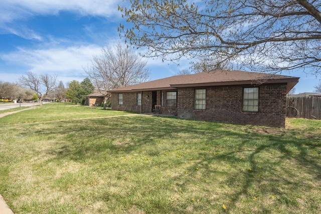 view of front of house featuring brick siding, a front lawn, and fence