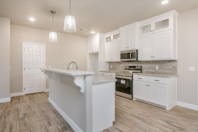 505 Pratt St, Claude, TX 79019 - kitchen featuring visible vents, a kitchen breakfast bar, light wood finished floors, stainless steel appliances, and backsplash