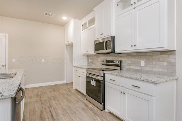 505 Pratt St, Claude, TX 79019 - kitchen with light wood-type flooring, stainless steel appliances, tasteful backsplash, and visible vents