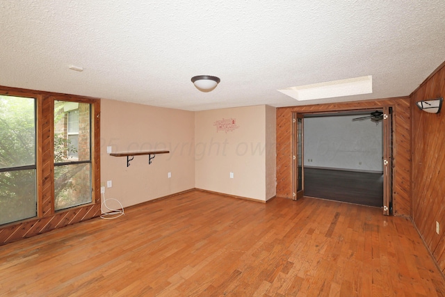 5507 Harvard St, Amarillo, TX 79109 - spare room featuring a textured ceiling, light wood-style flooring, wooden walls, and a skylight