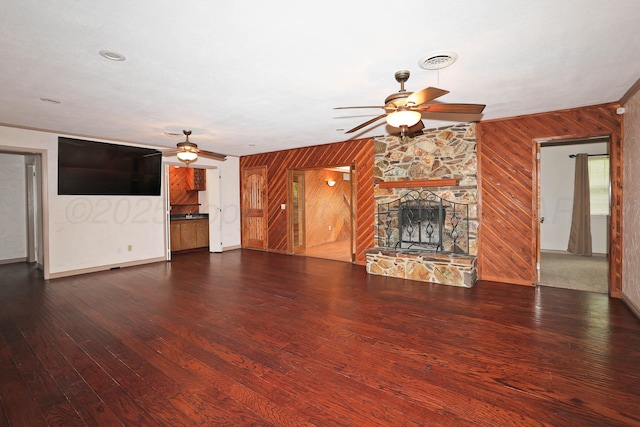5507 Harvard St, Amarillo, TX 79109 - unfurnished living room with a ceiling fan, wood walls, hardwood / wood-style floors, a stone fireplace, and baseboards