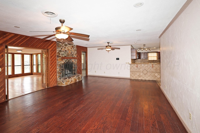 5507 Harvard St, Amarillo, TX 79109 - unfurnished living room featuring ceiling fan, dark wood-style floors, a stone fireplace, baseboards, and healthy amount of natural light