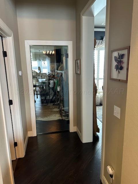 corridor with dark wood-type flooring and baseboards
