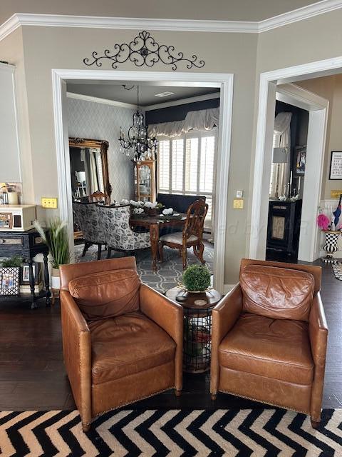 living area with an inviting chandelier, ornamental molding, and wood finished floors