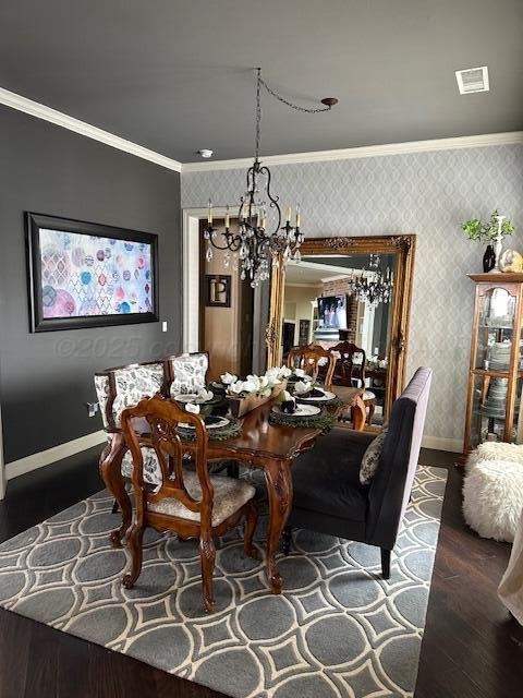 dining space with ornamental molding, wood finished floors, baseboards, wallpapered walls, and a chandelier