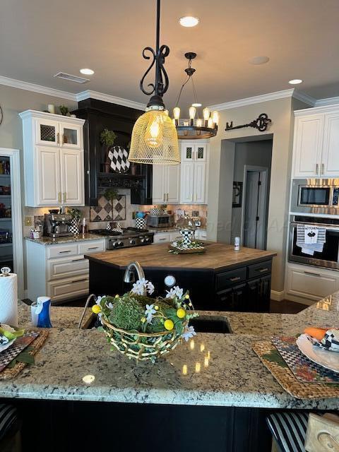 kitchen with crown molding, stainless steel appliances, light stone counters, and tasteful backsplash