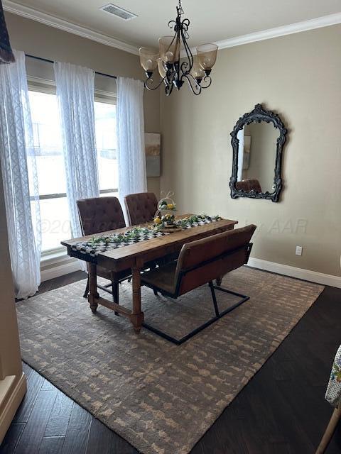 dining space with wood finished floors, ornamental molding, a chandelier, and visible vents
