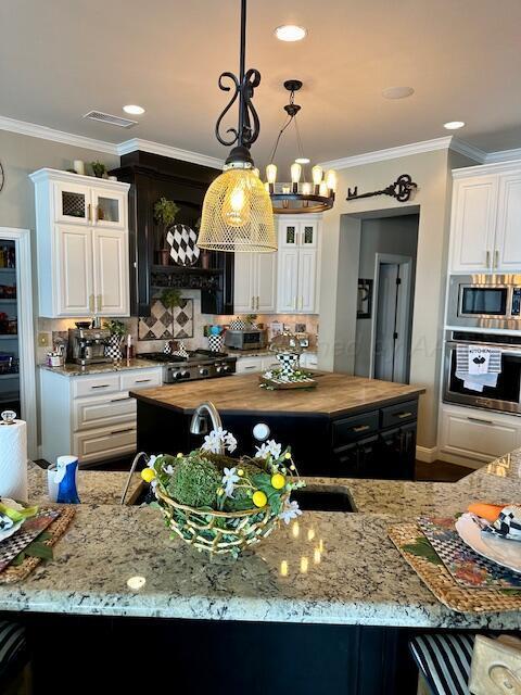 4301 Fairway Dr, Amarillo, TX 79124 - kitchen with stainless steel appliances, butcher block counters, a kitchen island, ornamental molding, and glass insert cabinets