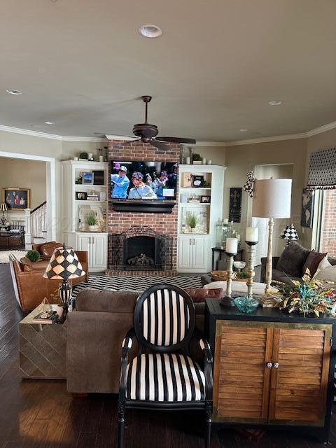 living room with a ceiling fan, crown molding, a brick fireplace, wood finished floors, and recessed lighting