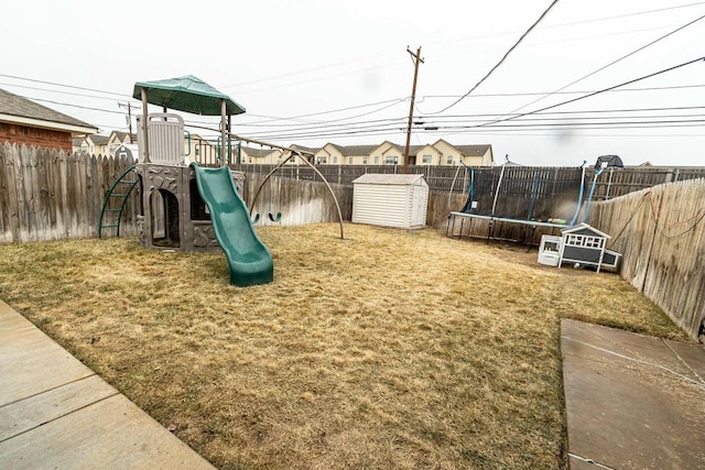 view of play area with a fenced backyard, a storage shed, and a trampoline