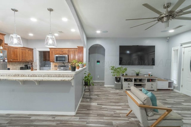 living room featuring recessed lighting, wood finished floors, arched walkways, and ceiling fan