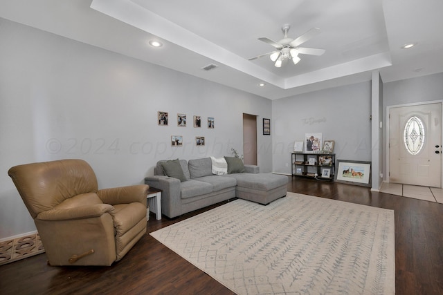 living room featuring hardwood / wood-style floors, ceiling fan, and a raised ceiling