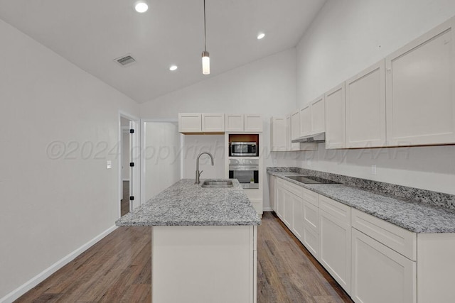 4204 Roxton Dr, Amarillo, TX 79109 - kitchen with stainless steel appliances, under cabinet range hood, a kitchen island with sink, dark wood-type flooring, and white cabinetry
