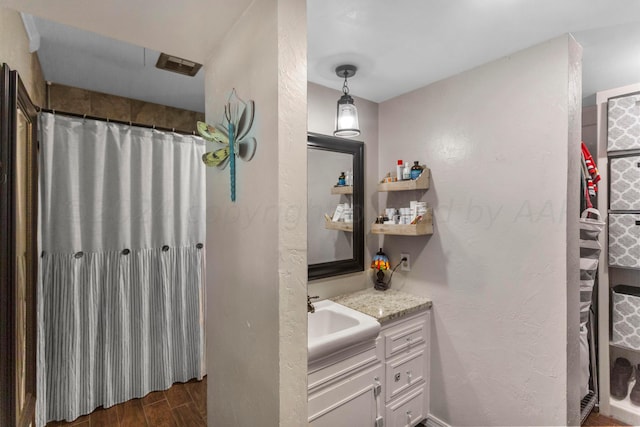 bathroom with walk in shower, vanity, and wood-type flooring